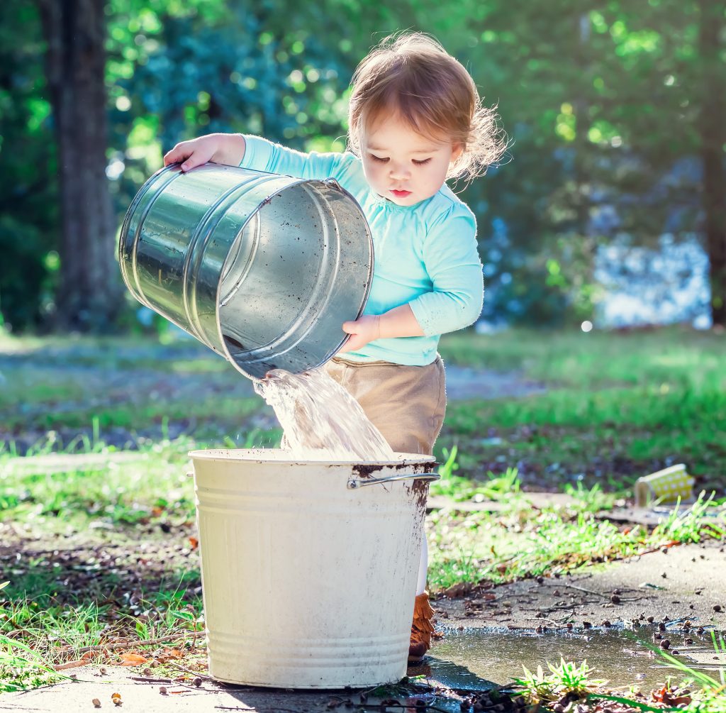 girl pouring water into a bucket